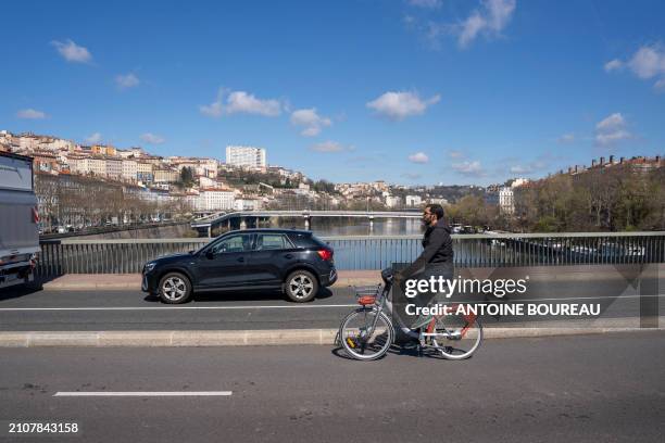 Man seen from behind riding a Velov on a cycle path on the Pont Morand in Lyon, France on 19 March 2024.