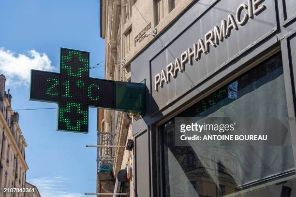 Display of the outside temperature on the facade of a chemist shop at 21 degrees, a temperature higher than the seasonal norm and illustrating the...