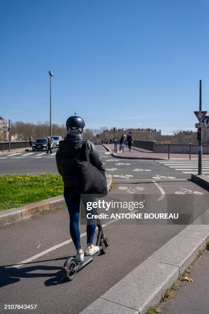 Young woman seen from the back riding a scooter with a helmet on a cycle path between Place Louis Pradel and Pont Morand in Lyon, France on 19 March...