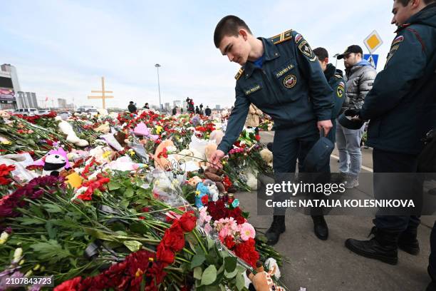 Russian Emergency Ministry cadets lay flowers at a makeshift memorial in front of the burnt-out Crocus City Hall concert venue in Krasnogorsk,...