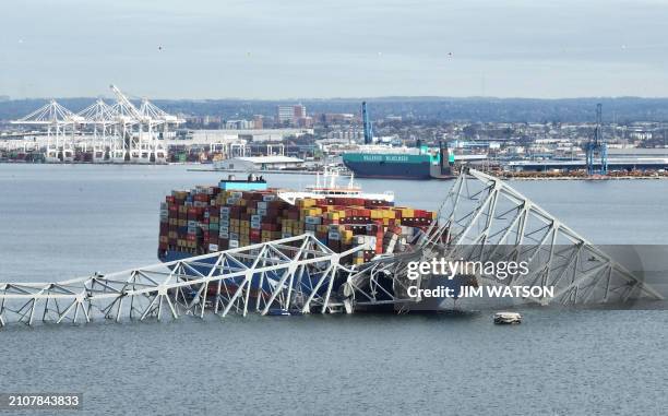 In this aerial image, the steel frame of the Francis Scott Key Bridge sits on top of a container ship after the bridge collapsed, Baltimore,...