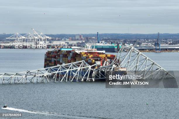 In this aerial image, the steel frame of the Francis Scott Key Bridge sits on top of a container ship after the bridge collapsed, Baltimore,...