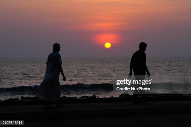 Man and a woman are walking on the street at sunset in Colombo, Sri Lanka, on March 26, 2024.