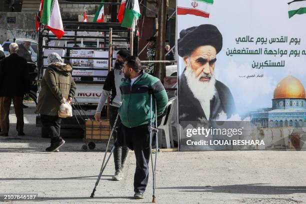 Portrait of Iran's late supreme leader Ayatollah Ruhollah Khomeini stands as Palestinians walk at the entrance of the Yarmuk camp for Palestinian...