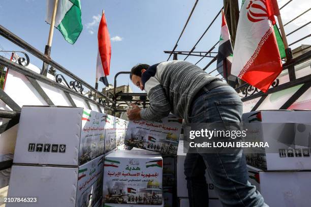 Man carries a box from the back of a truck at the entrance of the Yarmuk camp for Palestinian refugees, south of Damascus, during a delivery of...