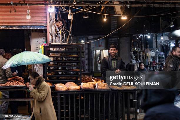 People walk past street vendors selling "Maarouk", a sweet pastry usually stuffed with dates or other sweet fillings consumed during the Muslim holy...