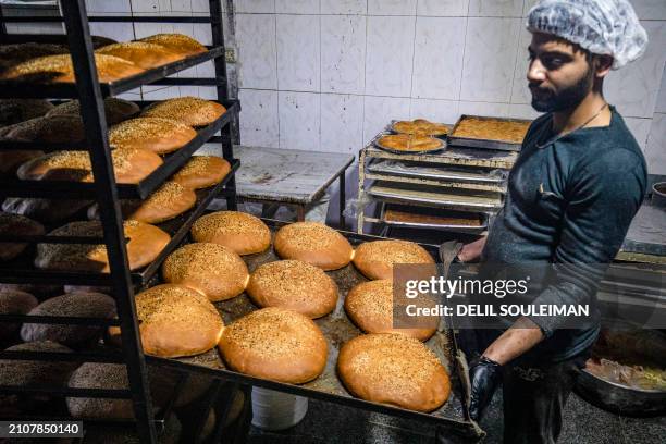 Man pulls a freshly baked batch of "Maarouk", a sweet pastry usually stuffed with dates or other sweet fillings consumed during the Muslim holy...