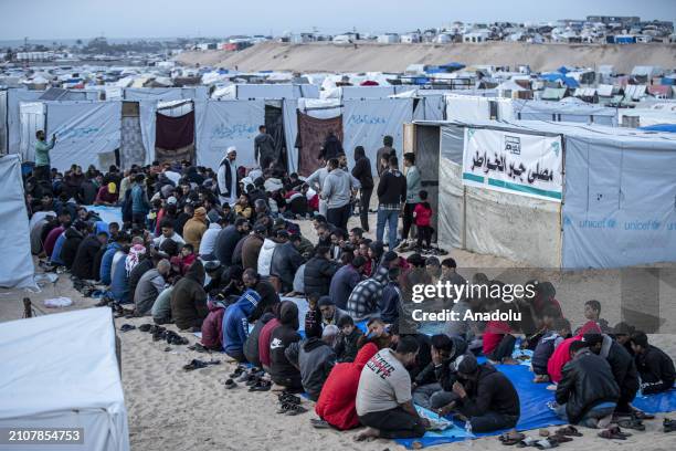 Displaced Palestinians gather to break their fast at a communal table set up amidst the tents as mass iftar dinner organized for displaced...