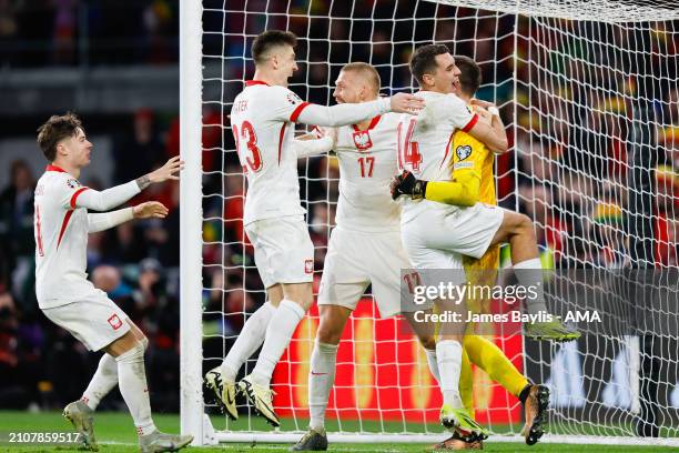 Wojciech Szczsny of Poland celebrates with his team mates after saving a penalty from Daniel James of Wales and winning the penalty shoot out to...