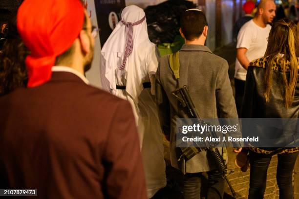 Man in a costume carries a gun while next to other people wearing costumes on Erev Purim on March 23, 2024 in Tel Aviv, Israel. The Jewish holiday of...