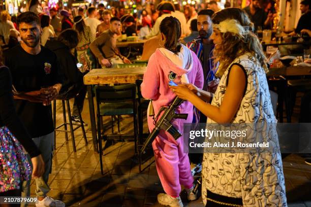 Woman wearing a costume carries a gun while out on Dizengoff celebrate Purim on Erev Purim on March 23, 2024 in Tel Aviv, Israel. The Jewish holiday...