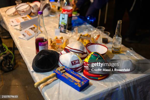 Noise maker and head coverings and purim items are displayed on a table during a Megila reading on Erev Purim on March 23, 2024 in Tel Aviv, Israel....