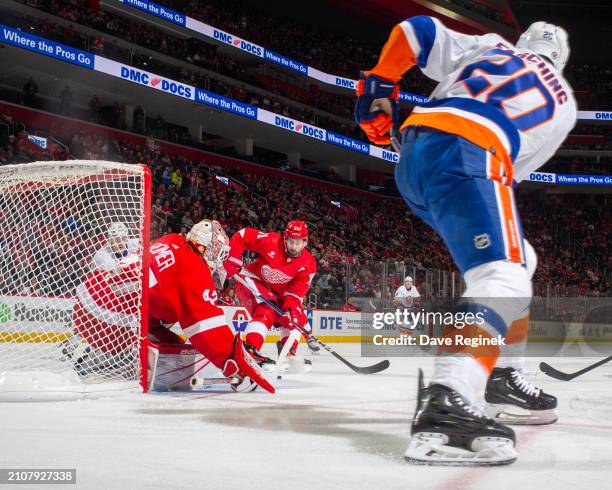 James Reimer and Dylan Larkin of the Detroit Red Wings defend the front of the net on a pass by Hudson Fasching of the New York Islanders during the...