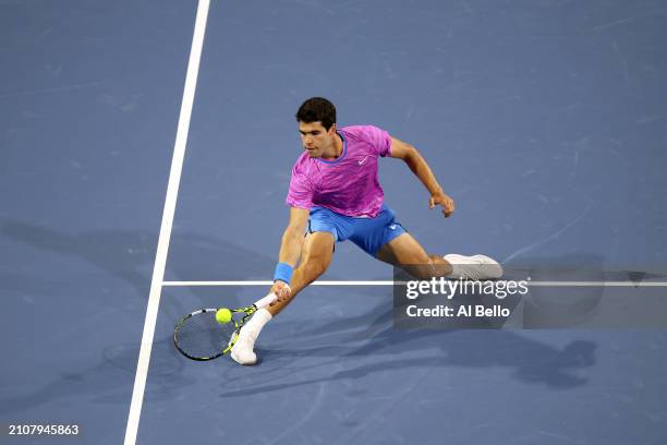 Carlos Alcaraz of Spain returns a shot against Roberto Carballes Baena of Spain during their match on day 8 of the Miami Open at Hard Rock Stadium on...