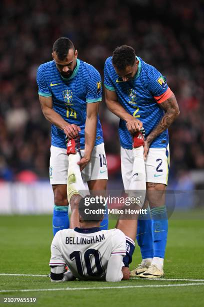 Fabricio Bruno and Danilo of Brazil sportingly help Jude Bellingham of England with his crampduring the international friendly match between England...