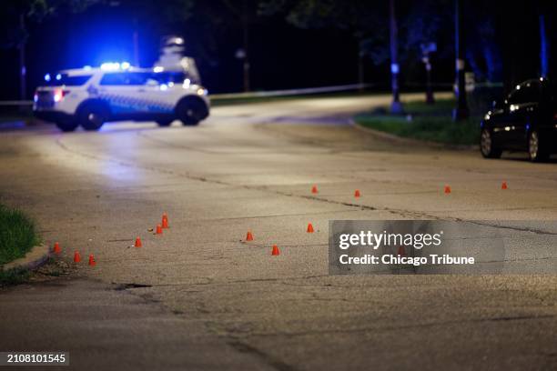 Evidence markers line the street at the scene where at least four people were shot, one fatally, near East 57th Street and Morgan Drive in Washington...