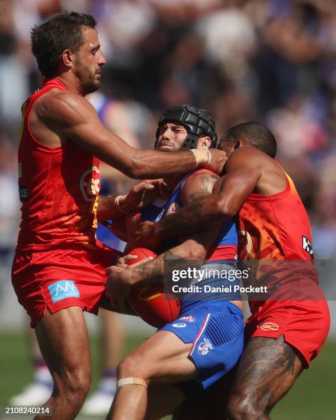 Caleb Daniel of the Bulldogs is tackled by Touk Miller of the Suns and Ben Long of the Suns during the round two AFL match between Western Bulldogs...