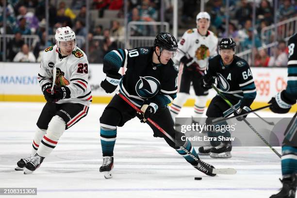 Klim Kostin of the San Jose Sharks controls the puck in front of Philipp Kurashev of the Chicago Blackhawks at SAP Center on March 23, 2024 in San...