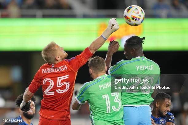 William Yarbrough of the San Jose Earthquakes punches the ball away from Jordan Morris and Yeimar Gomez of the Seattle Sounders FC during a game...