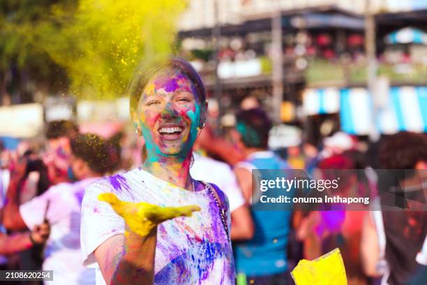 touristen in einer gruppe feiern freudig holi, indem sie mit buntem pulver spielen und so eine festliche atmosphäre voller glück und fröhlichkeit schaffen. - holi stock-fotos und bilder