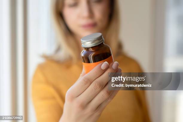 femme tenant une bouteille de supplément - complément vitaminé photos et images de collection