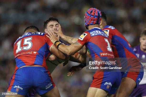 Trent Loiero of the Storm is tackled by Kalyn Ponga and Daniel Saifiti of the Knights during the round three NRL match between Newcastle Knights and...