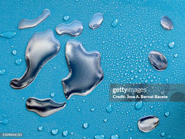 drops of silver metallic liquid slides on a soft blue background with small water bubbles. - mercurio fotografías e imágenes de stock