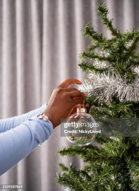 primo piano delle mani della ragazza che decorano un albero di natale all'interno - nicky pende foto e immagini stock