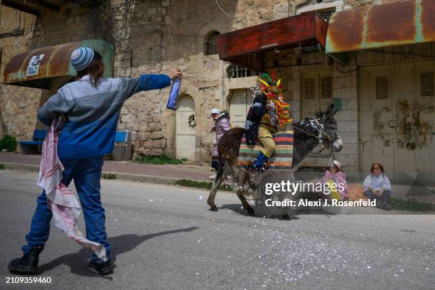 Jewish settler children spray each other with foam wearing costumes celebrate Purim as Israeli security forces secure the celebrations March 24, 2024...