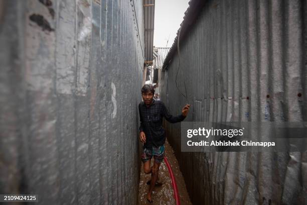 Man flees through an alleyway as a fire burns down his house in a slum dwelling on March 24, 2024 in the Banani neighbourhood of Dhaka, Bangladesh.