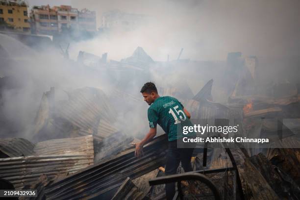 Man attempts to salvage belongings from a fire which engulfed a slum dwelling on March 24, 2024 in the Banani neighbourhood of Dhaka, Bangladesh.