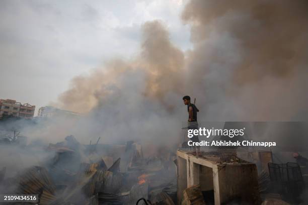 Man attempts to douse a fire which engulfed a slum dwelling on March 24, 2024 in the Banani neighbourhood of Dhaka, Bangladesh.