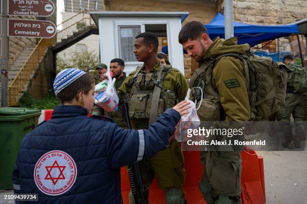Jewish settlers wearing costumes hand out gift baskets during the Purim parade as Israeli security forces secure the celebrations March 24, 2024 in...