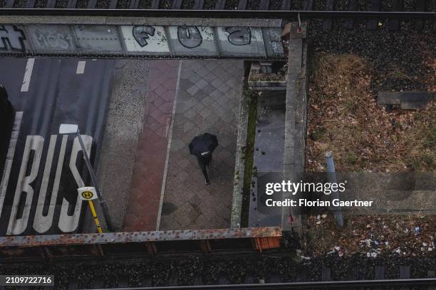 Person with umbrella walks on a pavement on March 22, 2024 in Berlin, Germany.