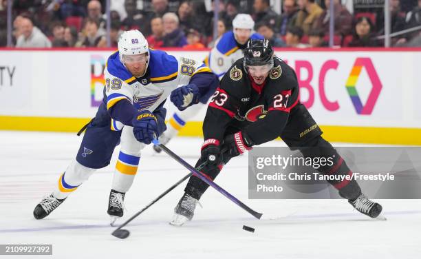 Pavel Buchnevich of the St. Louis Blues pokes the puck away while battling with Travis Hamonic of the Ottawa Senators during the third period at...