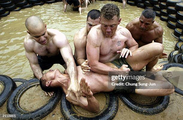 Soldiers wrestle with South Korean soldiers in a muddy ring during a joint ranger training exercise at a ranger camp near the demilitarised zone June...