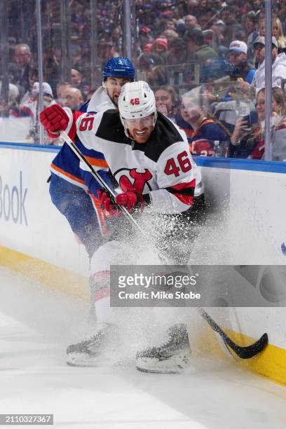 Max Willman of the New Jersey Devils checks Adam Pelech of the New York Islanders into the boards at UBS Arena on March 24, 2024 in Elmont, New York.