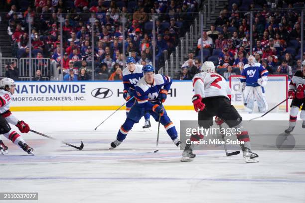 Mathew Barzal of the New York Islanders controls puck against Brendan Smith and Dawson Mercer of the New Jersey Devils at UBS Arena on March 24, 2024...