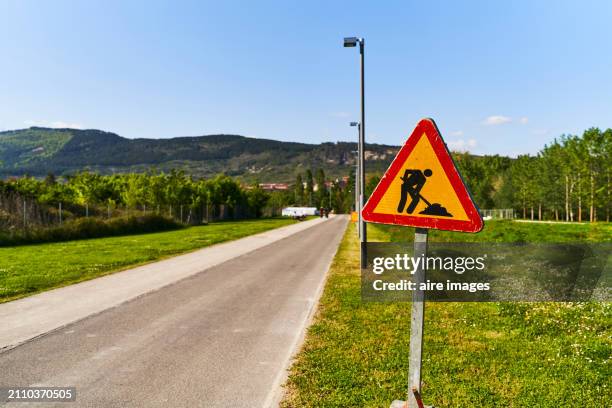 front view of a sign of works samples on the side of a road without people around - sinal de perigo sinal imagens e fotografias de stock