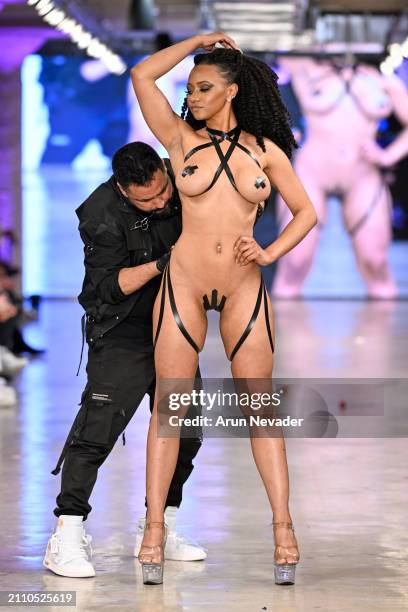 Designer Drakhan Blackhart applies tape on Angi Griffin on the runway for the Black Tape Project fashion show during the Los Angeles Fashion Week...