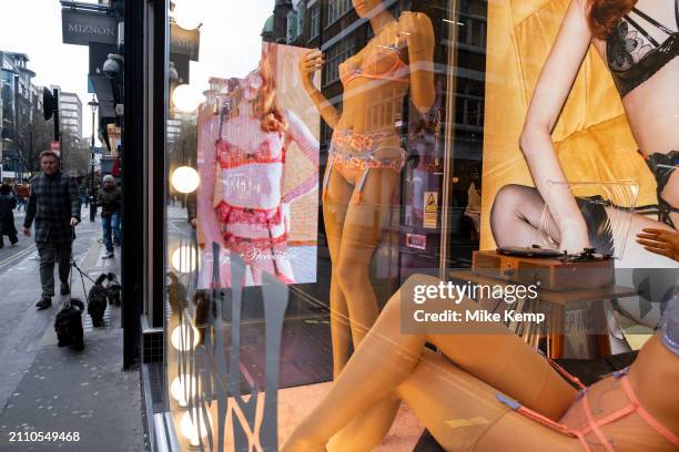 Digital advertising images of female models and mannequins wearing luxury underwear in the shop window of Agent Provocateur in Soho, interacting with...