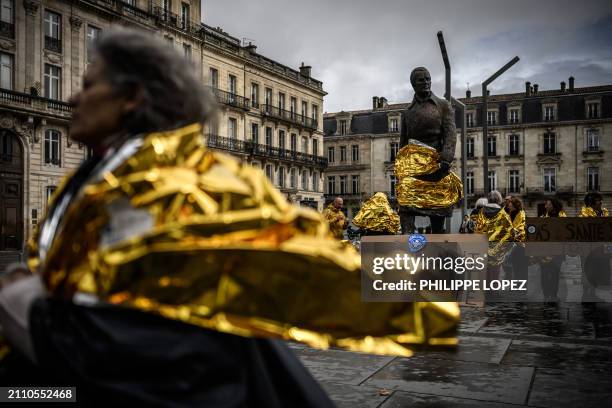 Demonstrators wrapped in survival blankets gather around the statue of former French Prime Minister and mayor of Bordeaux, Jacques Chaban-Delmas...