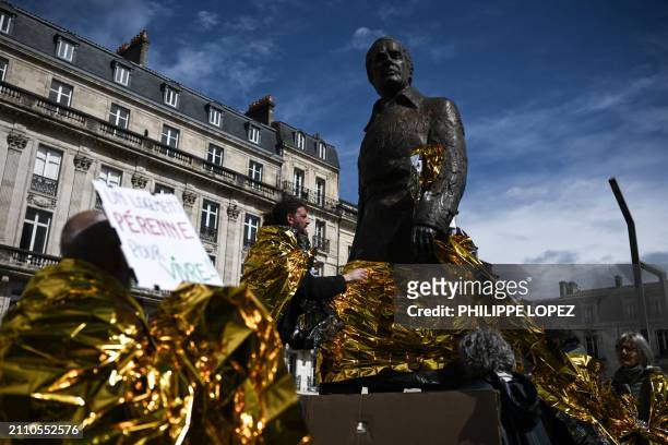Demonstrator wraps the statue of former French Prime Minister and mayor of Bordeaux, Jacques Chaban-Delmas with a survival blanket during a protest...
