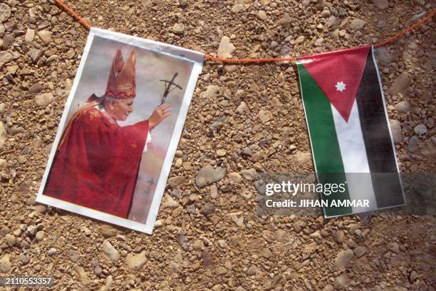 Picture of Pope John Paul II is strung alongside the Jordanian flag at Wadi Kharrar, 18 March 2000, three days before the pontiff's visit to the...