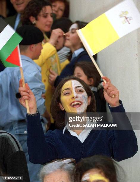 Jordanian waves the Vatican flag and her national flag as Pope John Paul II passes in his popemobile 20 March 2000 in Madaba. The Pope urged Arabs...