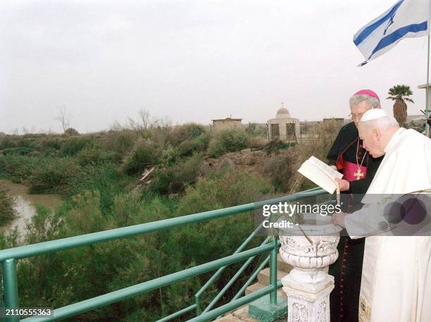 Pope John Paul II reads from a Bible under an Israeli flag in the West Bank site of Qasr al-Yahud 22 March 2000, on the banks of the River Jordan,...