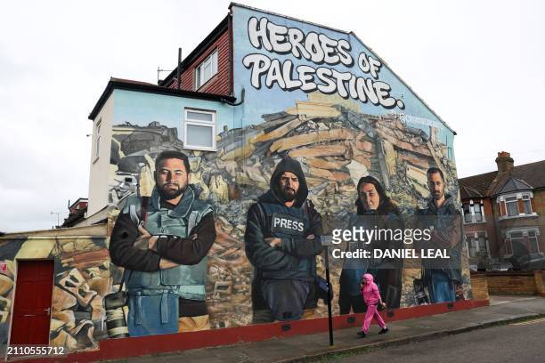 Pedestrian walks past a mural made by street artists Auberi Chen, Core 246 and Captain Kris depicting Palestinian photographers Mohammed Al-Masri ,...