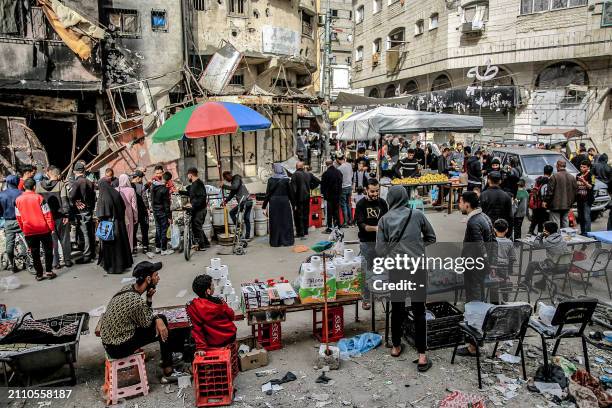 People shop from vendors in an open-air market amidst destruction in Gaza City on March 27, 2024 amid the ongoing conflict in the Gaza Strip between...