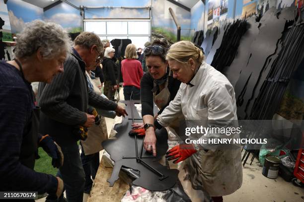 Janette Barton, wife of British artist Dan Barton, instructs volunteers how to fix metal stands to WW2 soldier silhouettes, during the preparation of...