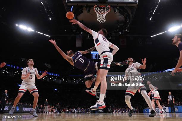 Donovan Clingan of the Connecticut Huskies blocks a shot by Boo Buie of the Northwestern Wildcats during the first half in the second round of the...